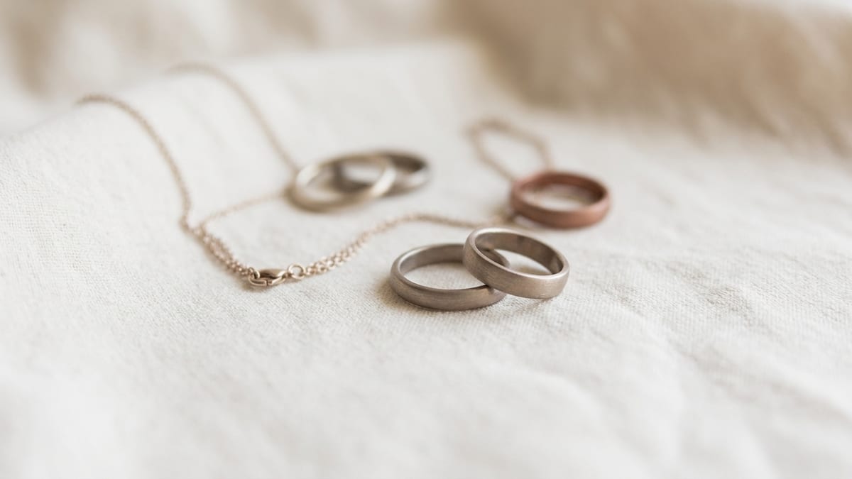 A few unbranded metal rings and a fine chain resting on a soft neutral surface
